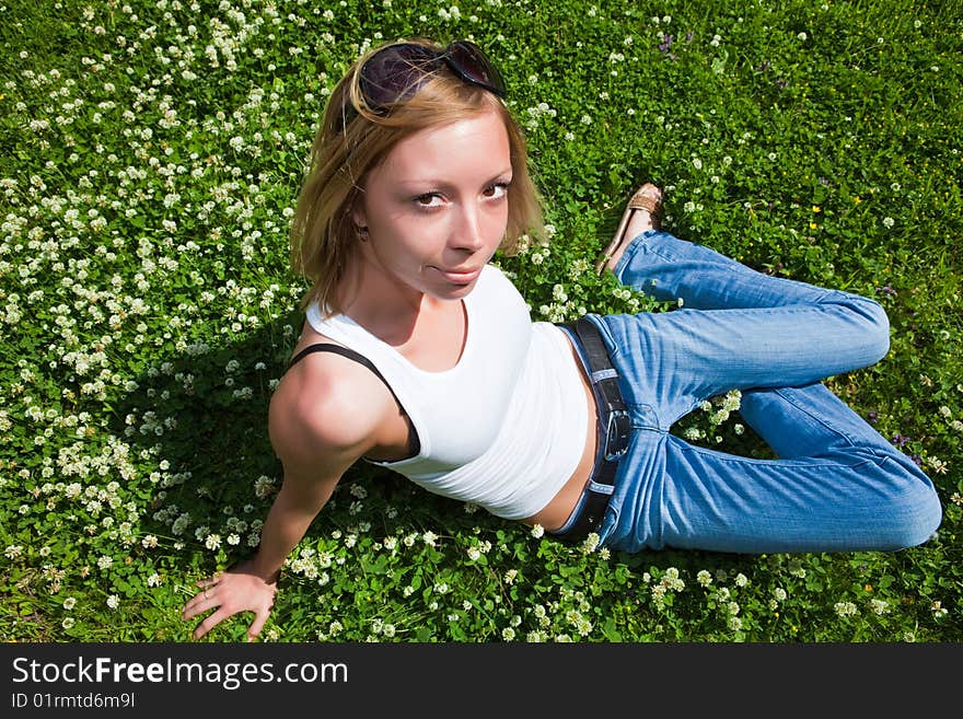 Beautiful young woman sits on a green grass. Beautiful young woman sits on a green grass