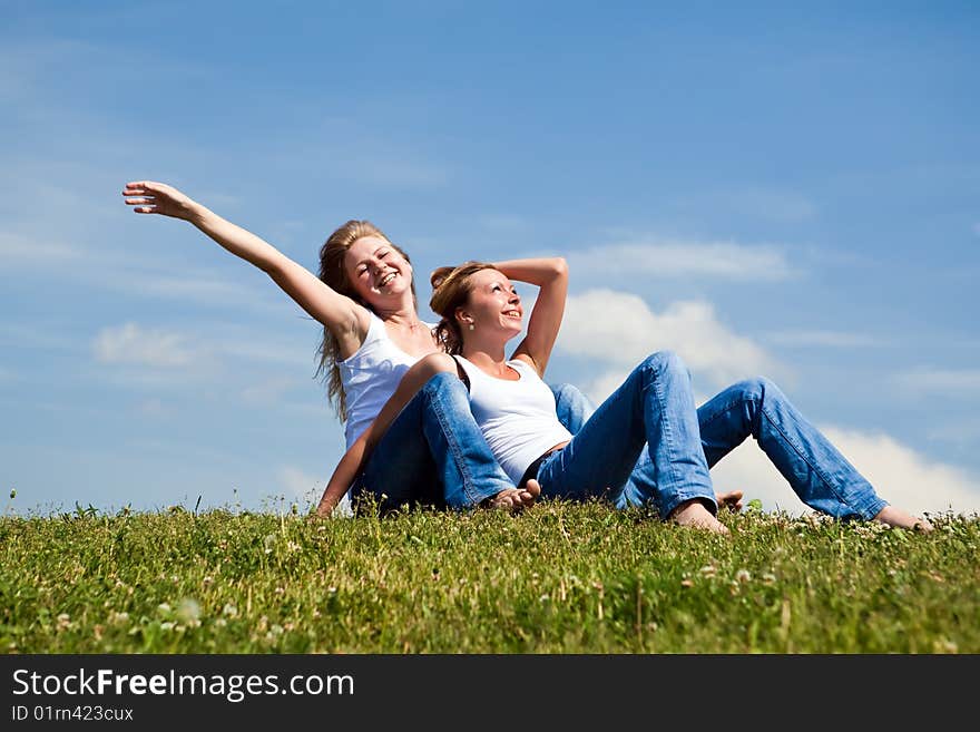 Two girls have a rest on a green grass. Two girls have a rest on a green grass