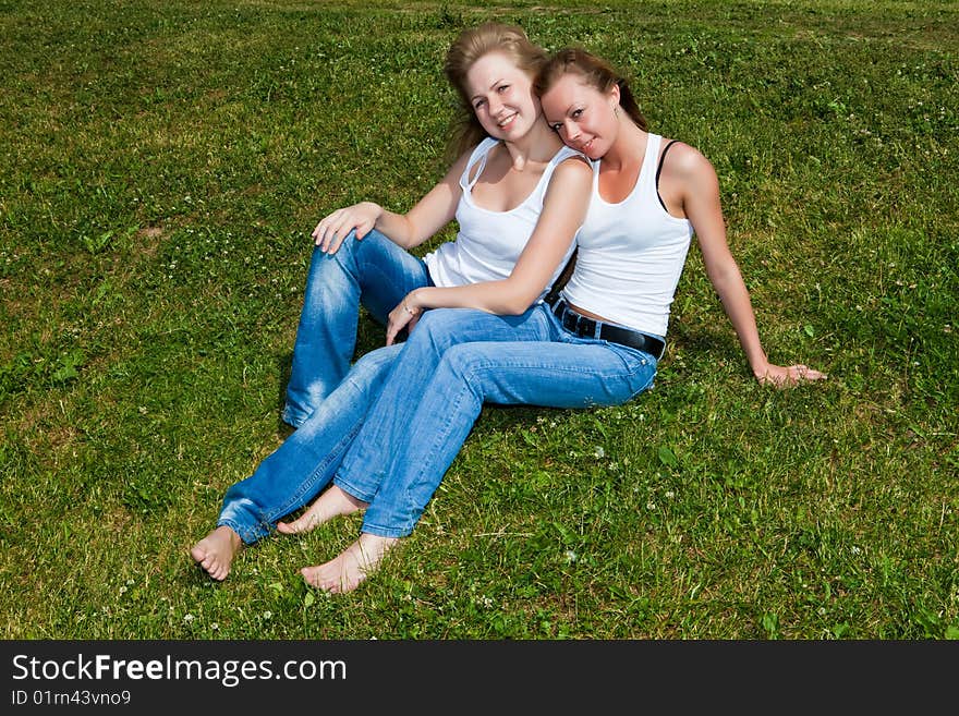 Two girls have a rest on a green grass