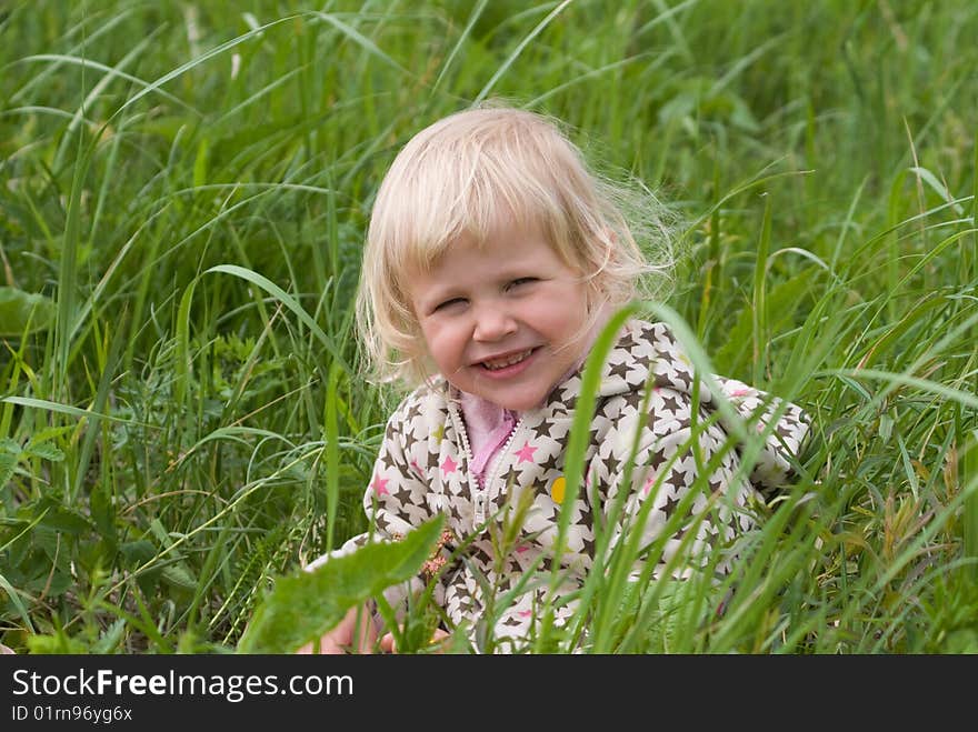 Beautiful girl is sitting in a field of grass. Beautiful girl is sitting in a field of grass