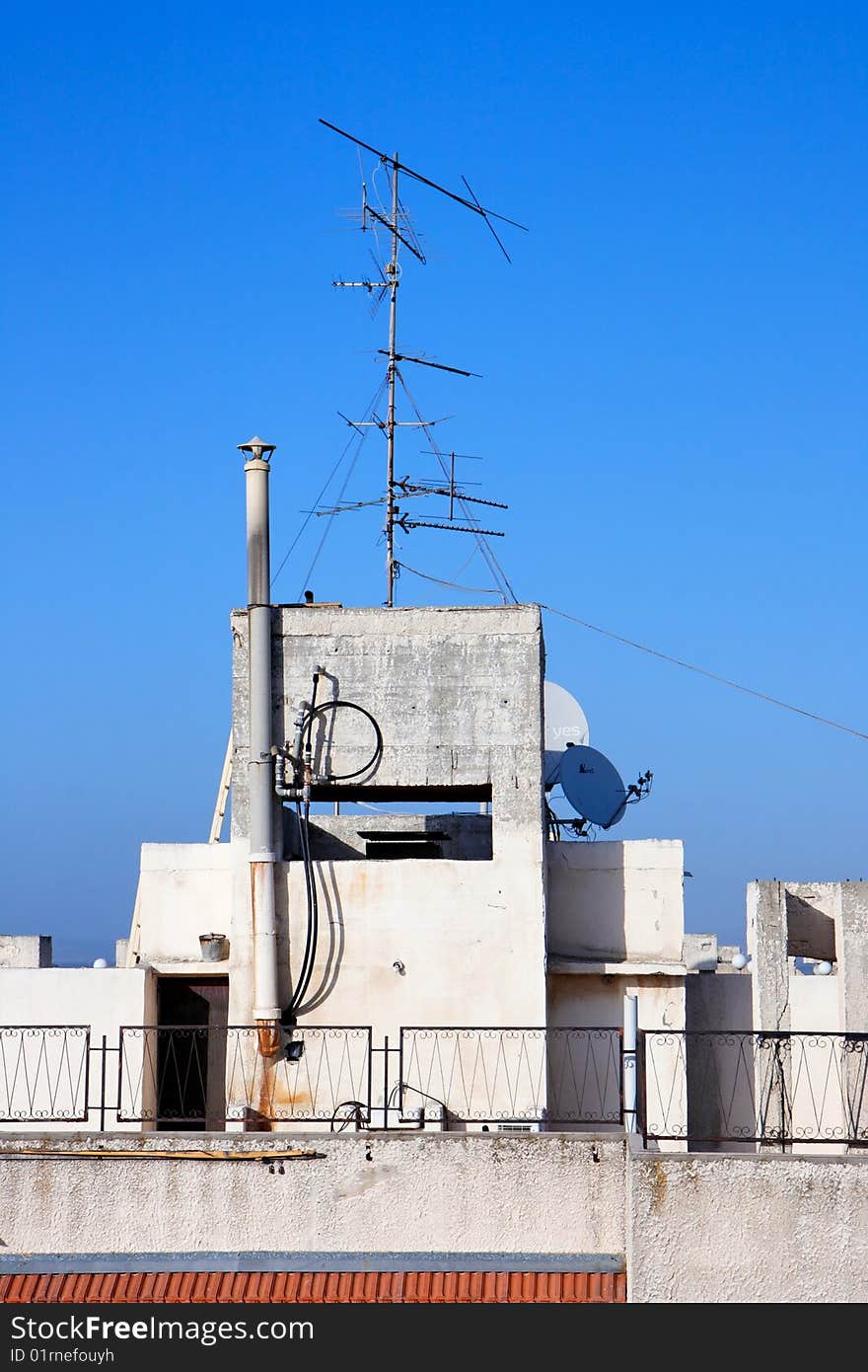 Old television aerial on house roof against blue sky