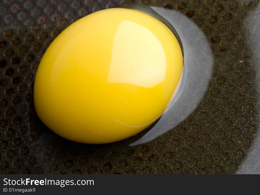 Broken egg on a black frying pan. closeup