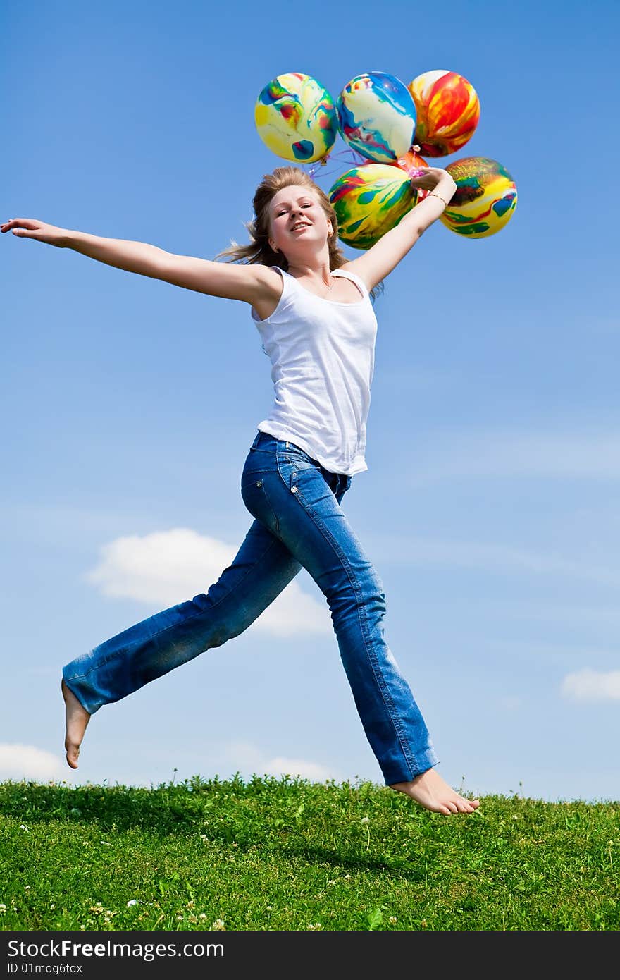 Girl jumps on a green grass with balloons in a hand. Girl jumps on a green grass with balloons in a hand