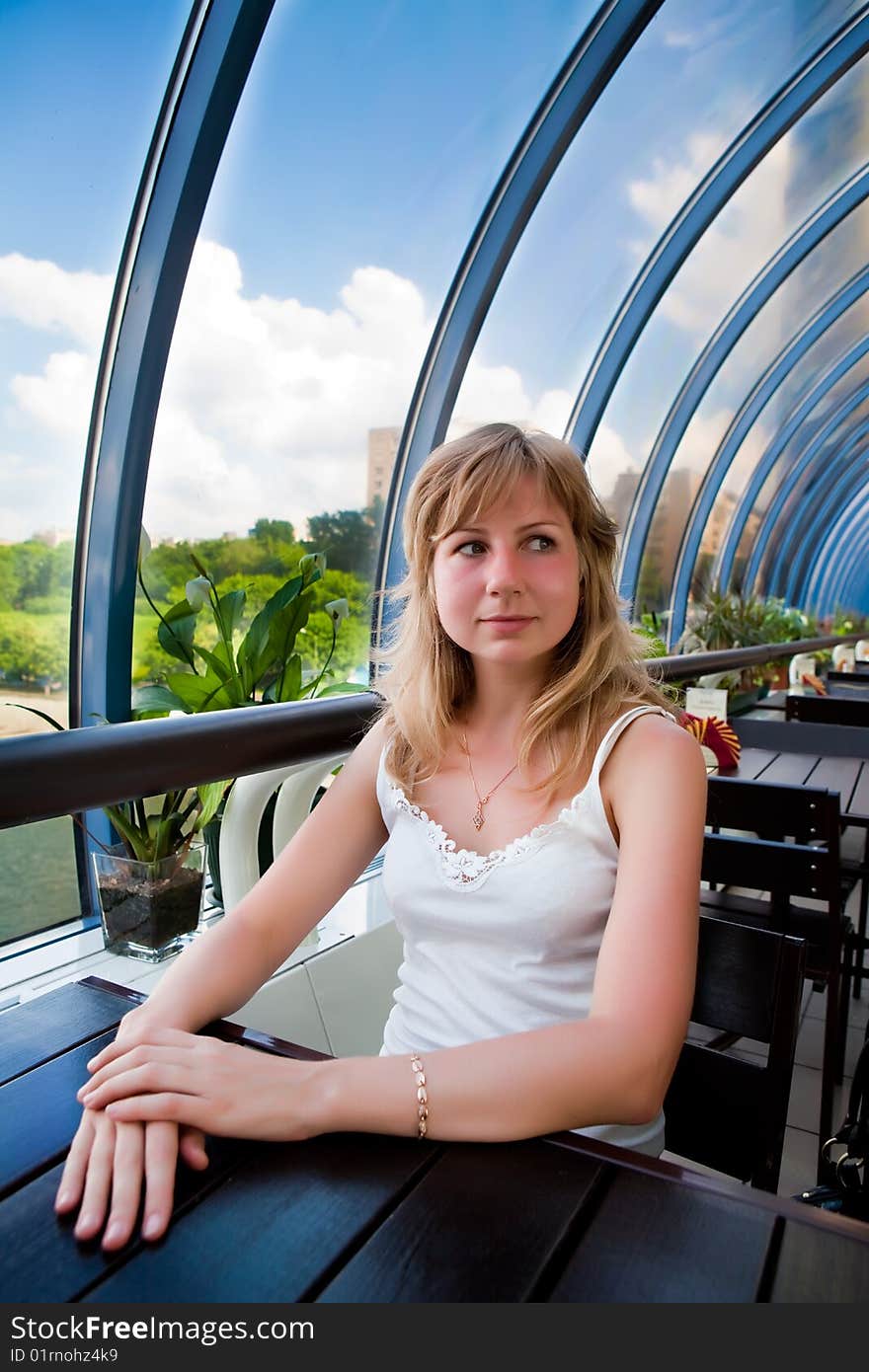 Beautiful girl sits at a table in cafe. Beautiful girl sits at a table in cafe