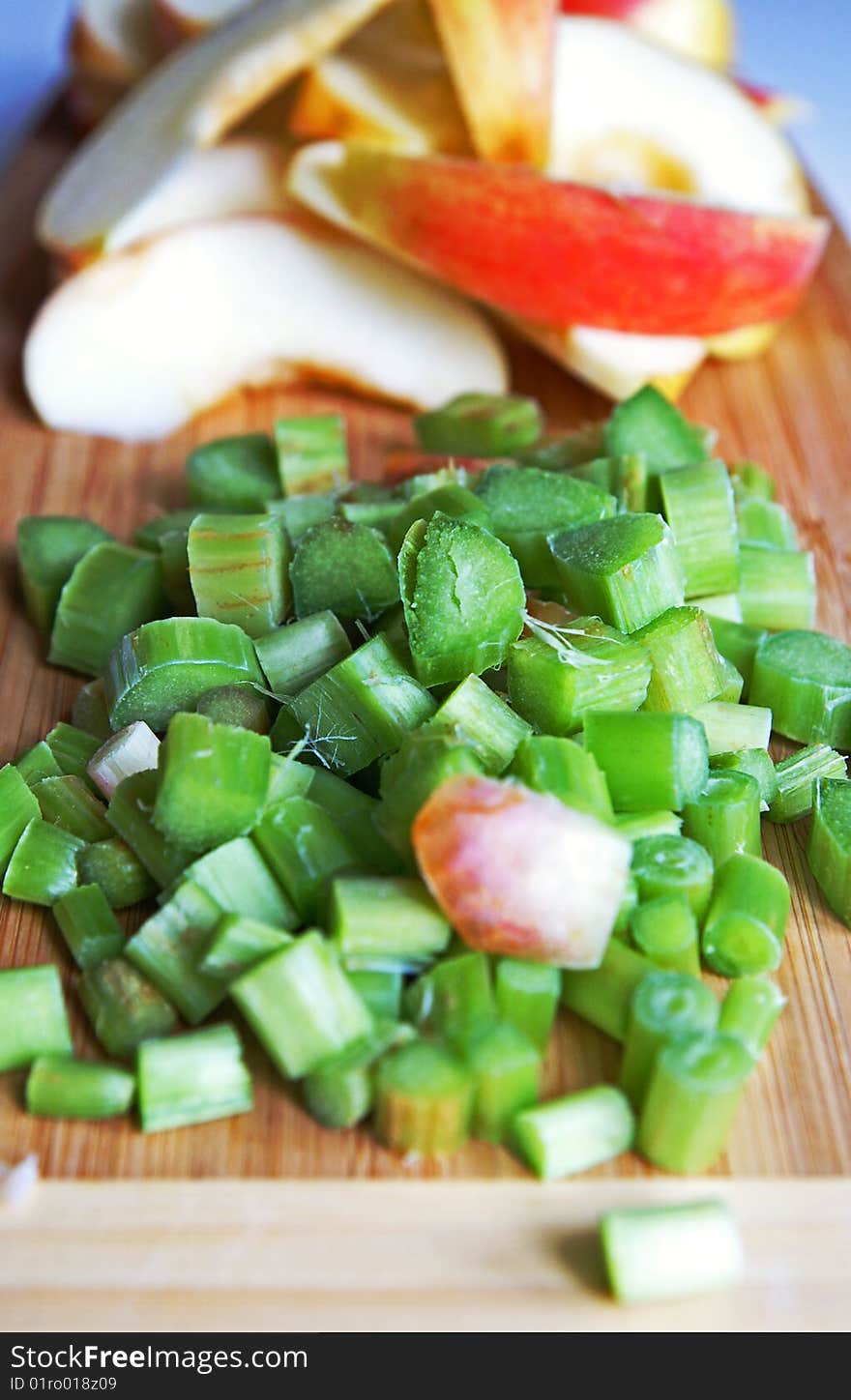 Red apple and green rhubarb cut for compote or jam cooking on a wooden kitchen board. Red apple and green rhubarb cut for compote or jam cooking on a wooden kitchen board