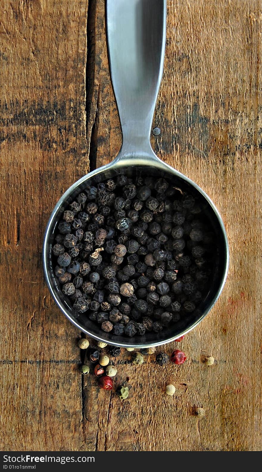 Black Peppercorns in a Metal Measuring Cup