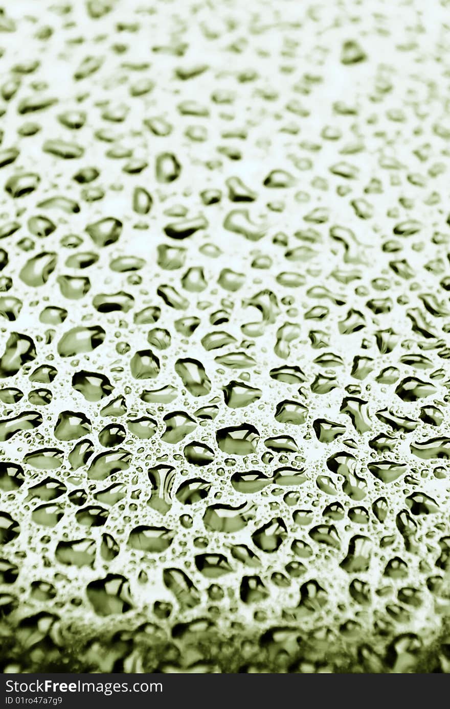 Fresh greenish drops of water on a glass surface. Selective focus this image. Fresh greenish drops of water on a glass surface. Selective focus this image