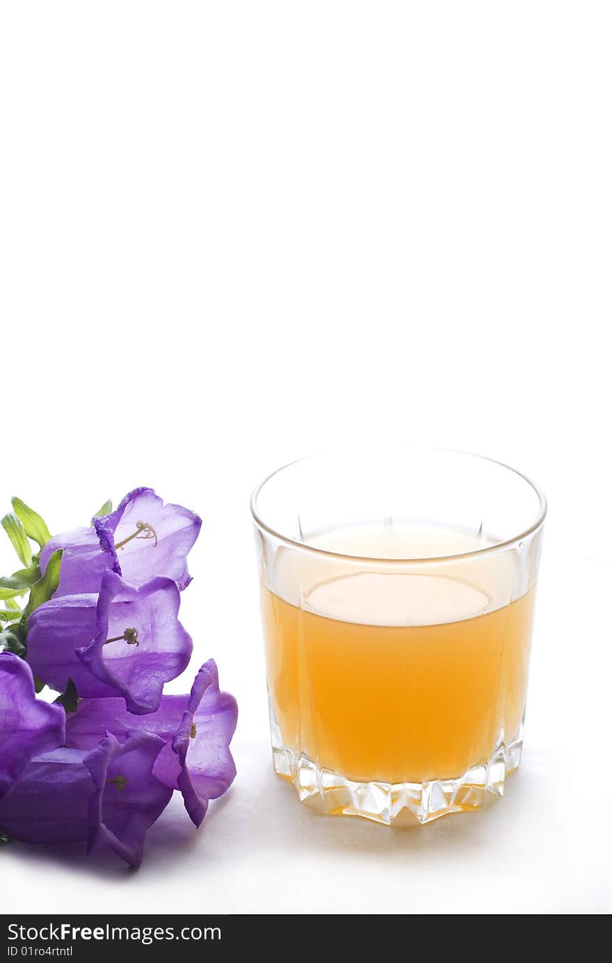 Glass of orange juice with bell-flowers cut-out on white background. Glass of orange juice with bell-flowers cut-out on white background