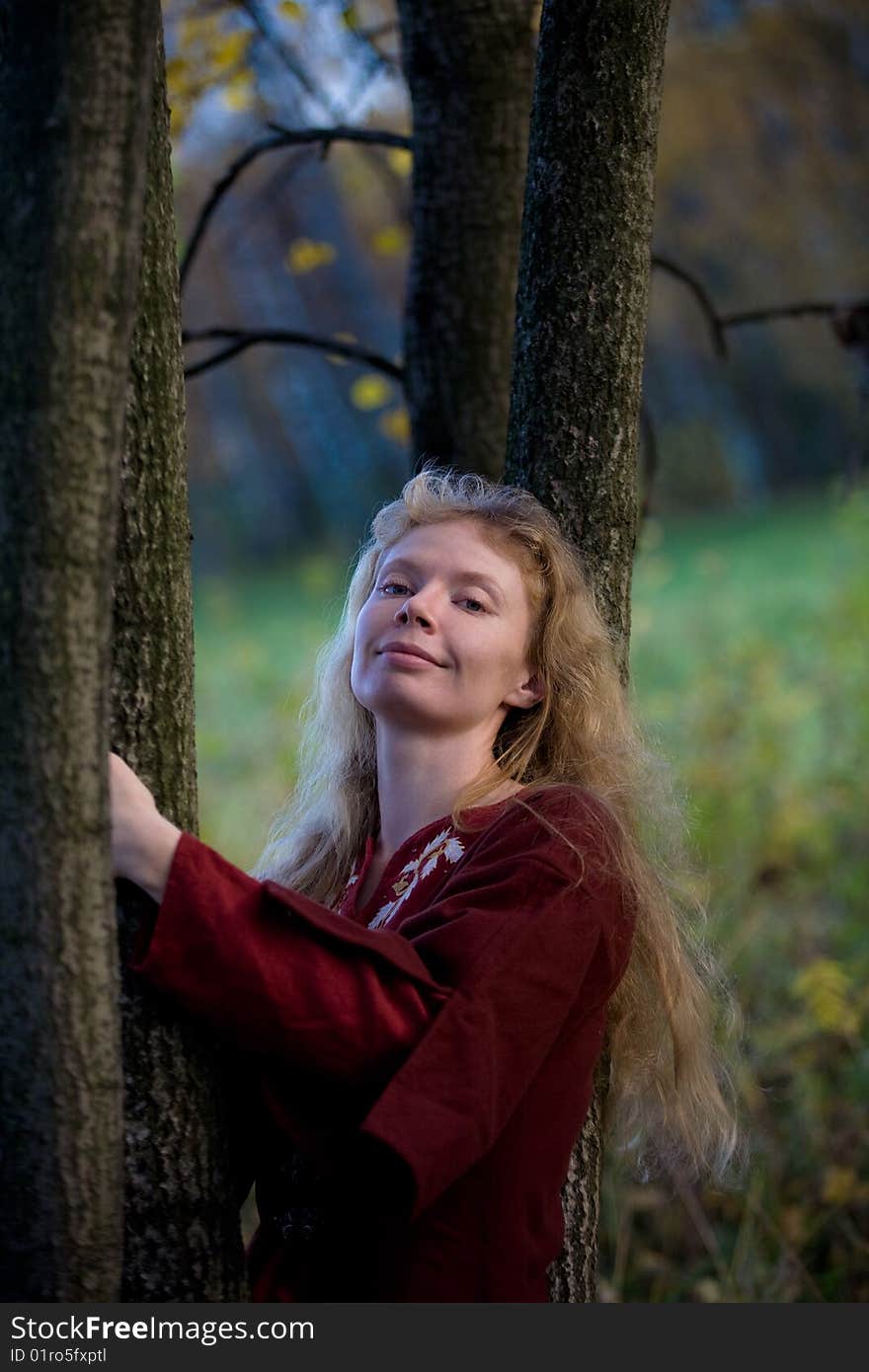 The blonde girl in medieval red dress in the autumn forest. The blonde girl in medieval red dress in the autumn forest