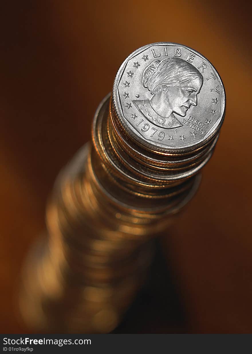 Overhead view of tall stack of balancing coins, dark brown background. Overhead view of tall stack of balancing coins, dark brown background.