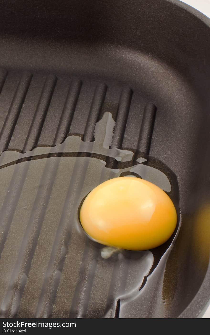 Broken egg on a black frying pan