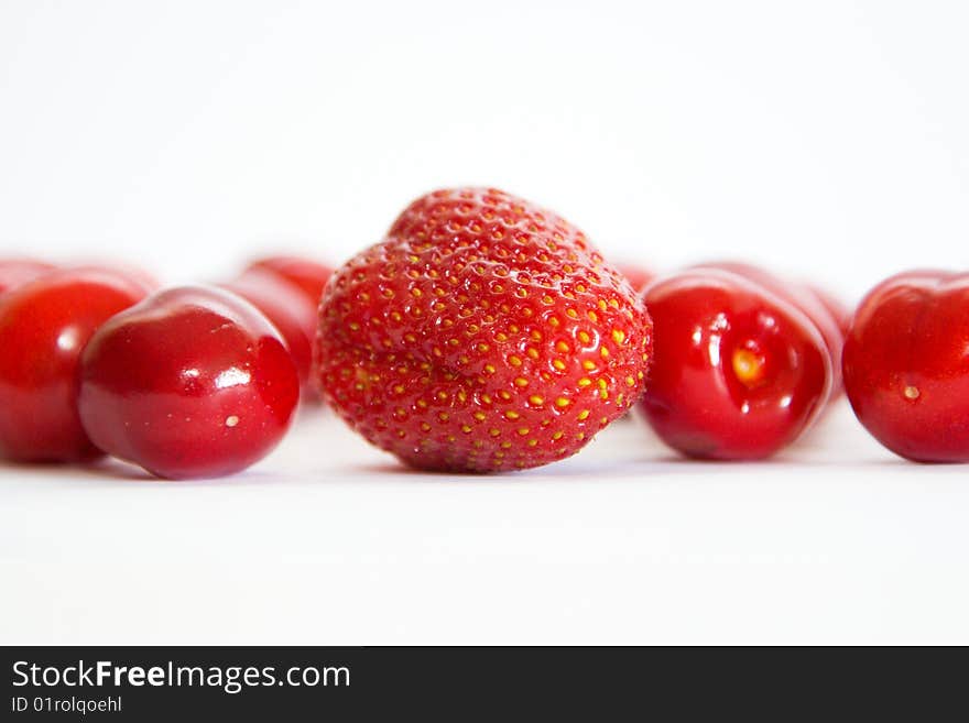 Separate berries of a sweet cherry abreast and one berry of the Strawberry