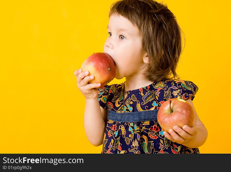 Little girl with two apple isolated on yellow background