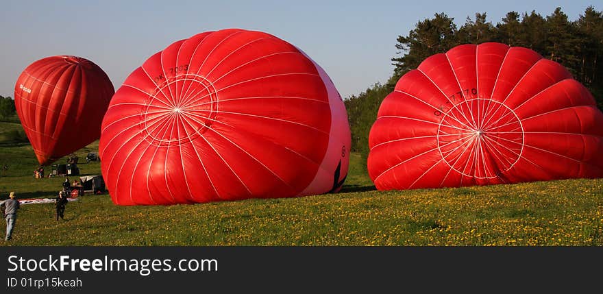 Three red hot air balloons during the start