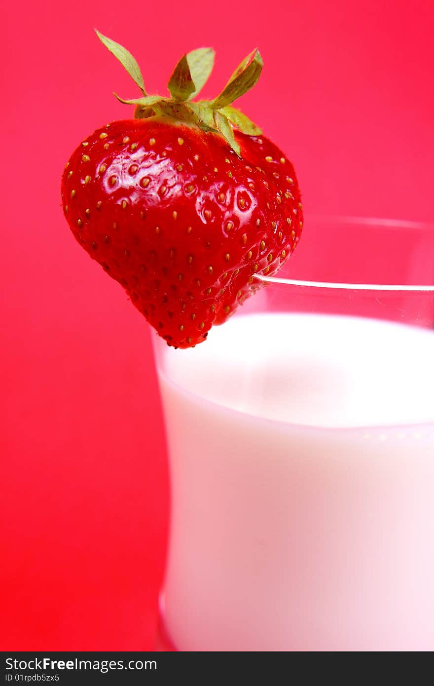 Photo of milk drink with strawberry on red background. Photo of milk drink with strawberry on red background