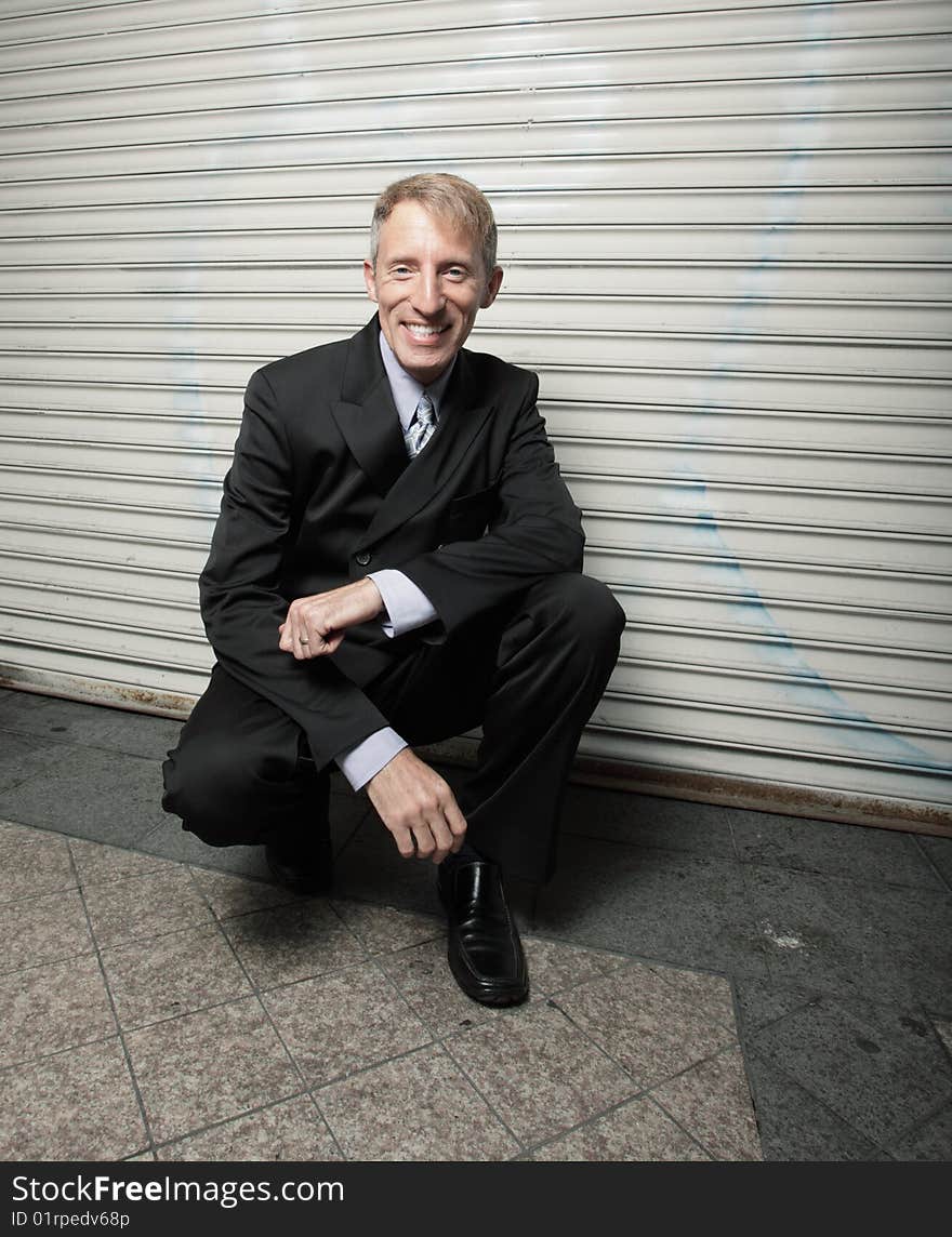 Businessman Squatting And Smiling