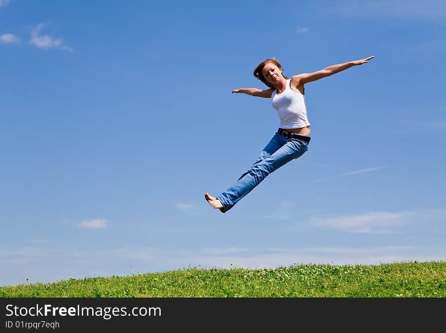 Girl jump on a green grass against the blue sky. Girl jump on a green grass against the blue sky