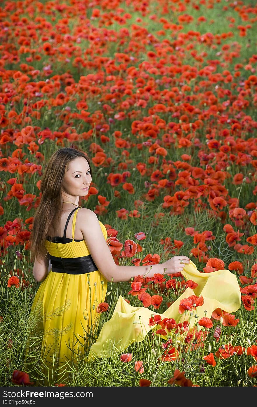 Beautiful young girl with yellow scarf in the poppy field, high angle view