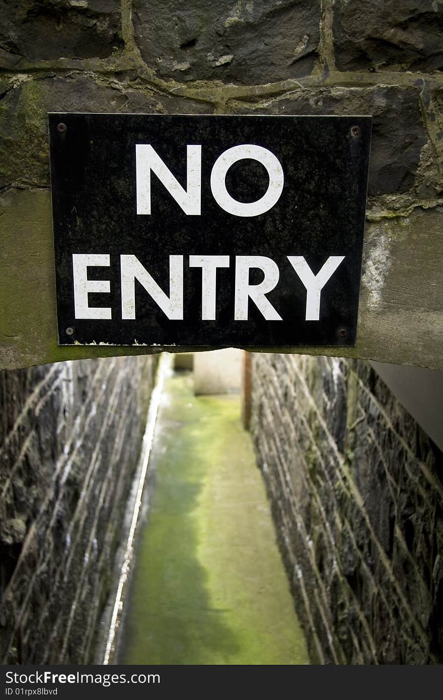 Clear sign at narrow pathway with stone walls. Clear sign at narrow pathway with stone walls