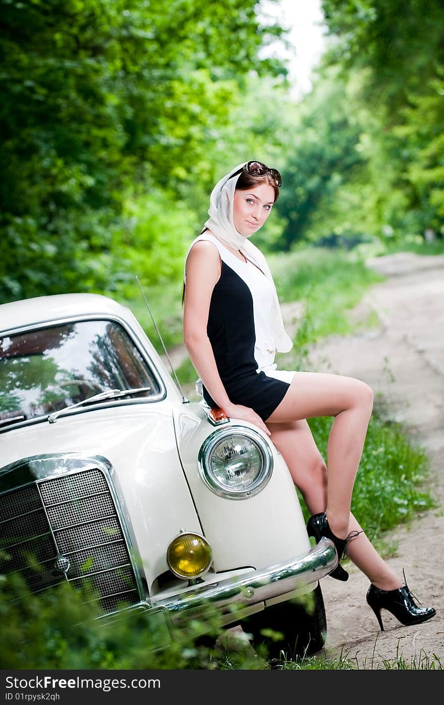 Beautiful pin-up styled girl sitting on retro car