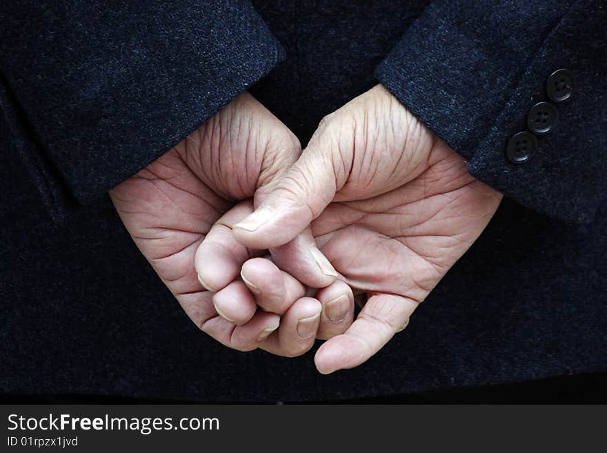 Dark blue jacket and two hands with crossed fingers.