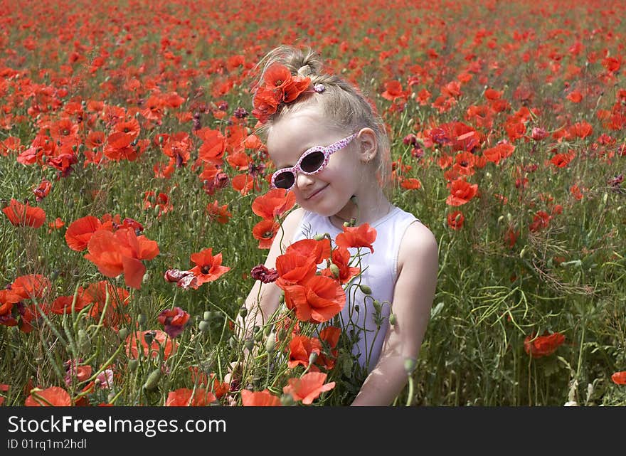 On the image there is a little girl. She is in  field of poppys. On the image there is a little girl. She is in  field of poppys.