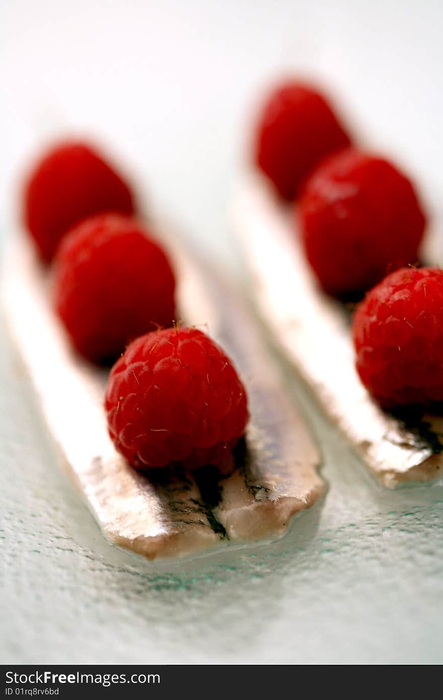 Fillets of anchovies with raspberries on a glass plate. Fillets of anchovies with raspberries on a glass plate