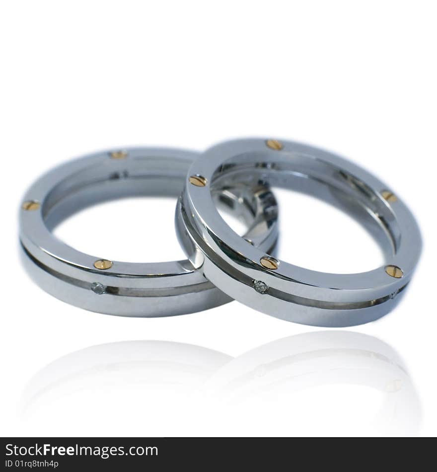 His and hers golden wedding bands, with diamonds. On a white background with soft reflection, isolated. His and hers golden wedding bands, with diamonds. On a white background with soft reflection, isolated.