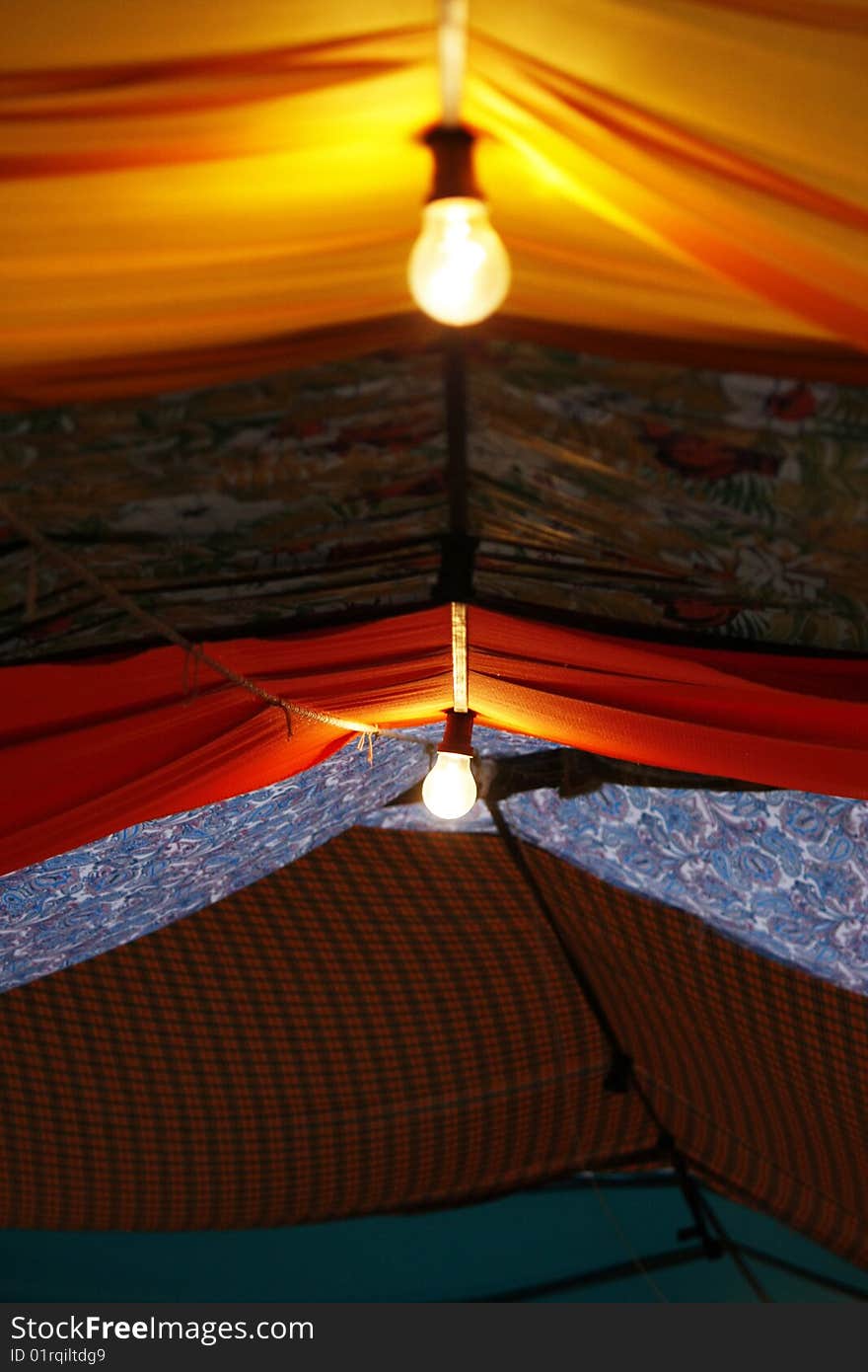 View of a street fair where the ceiling is made up of stiched pieces of cloth of various colors. View of a street fair where the ceiling is made up of stiched pieces of cloth of various colors.