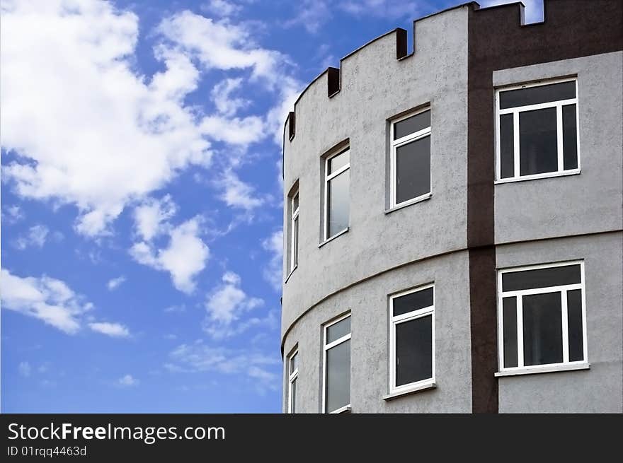 Edge of a tower-like new building with clouds on the background. Edge of a tower-like new building with clouds on the background