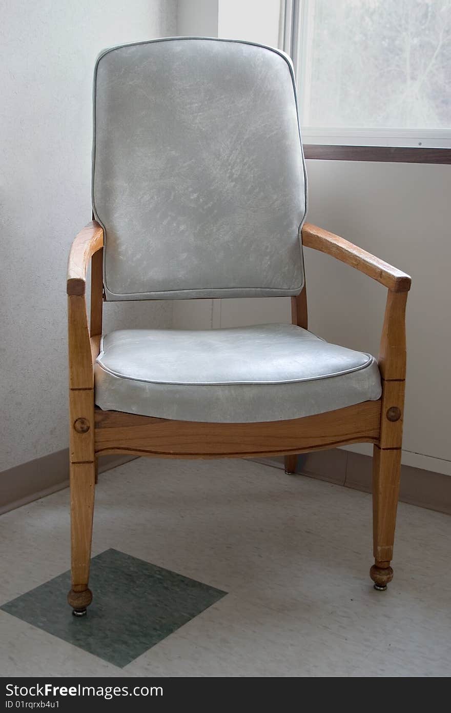 A lone chair sitting the corner of a hospital room. A lone chair sitting the corner of a hospital room