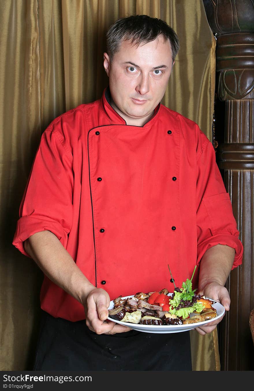 Cook takes off the fried meat and green-stuffs from a sword in a dish