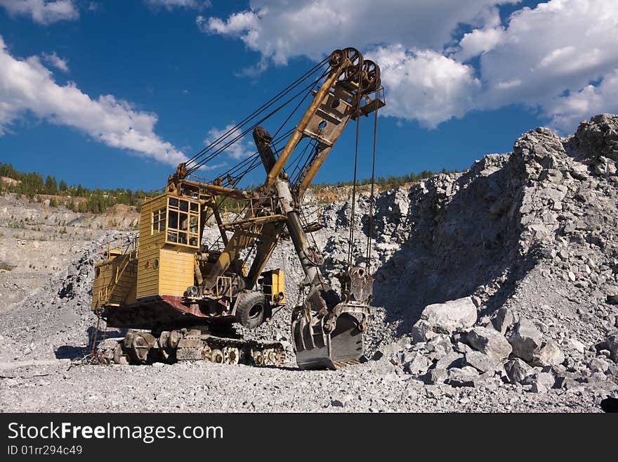 An excavator in opencast mine under skies. An excavator in opencast mine under skies