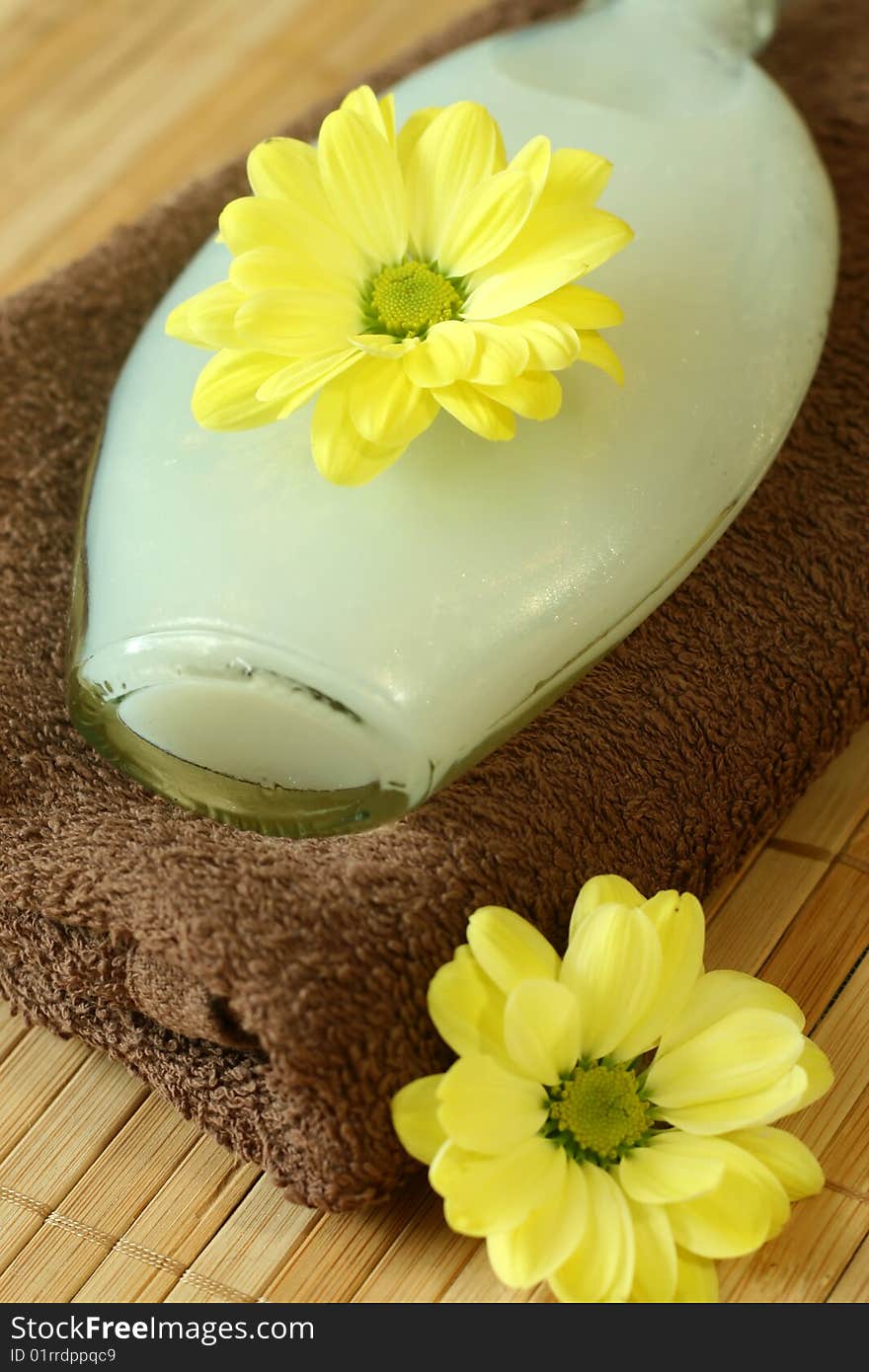 Spa composition of towel, bottle and yellow flowers.