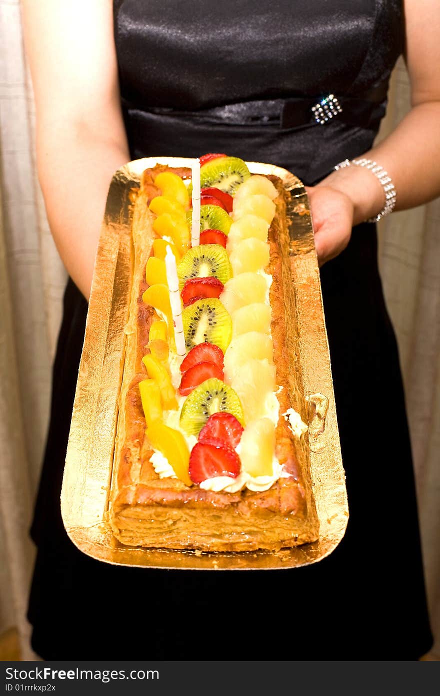 A birthday cake with candles and strawberries and oranges and kiwi