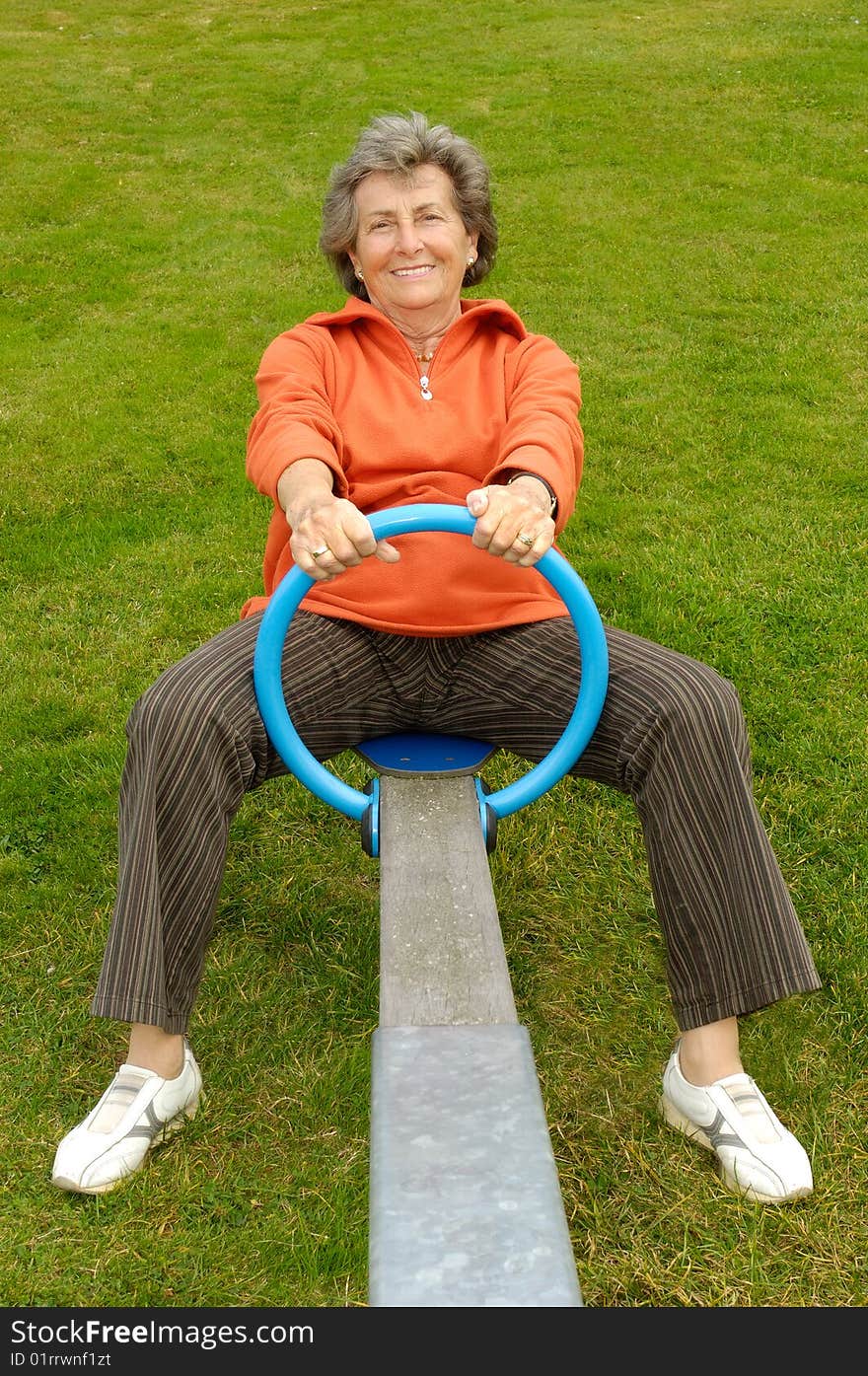 Happy senior woman in orange shirt on a playground. Happy senior woman in orange shirt on a playground