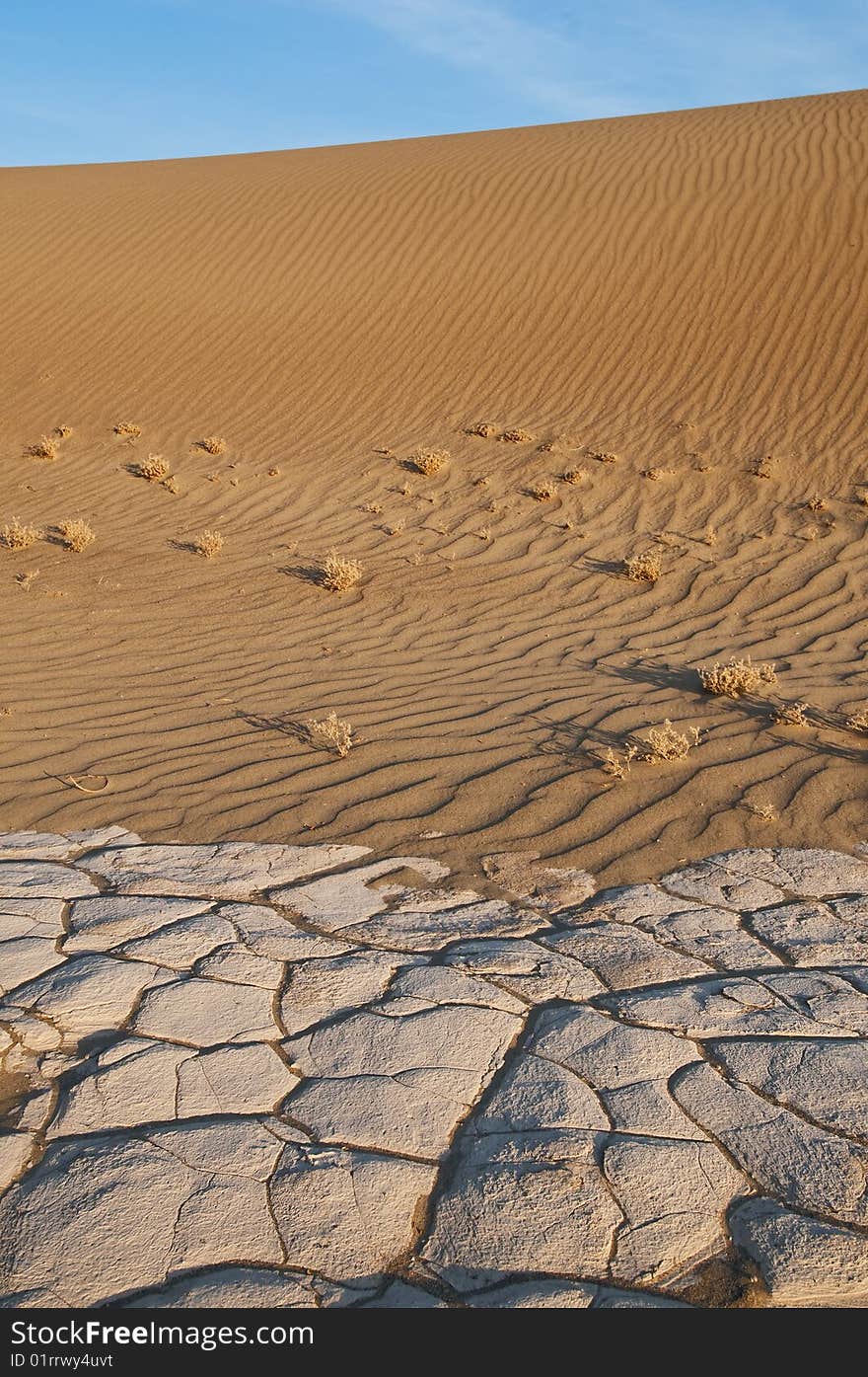 Sand dune with dry cracked earth in front