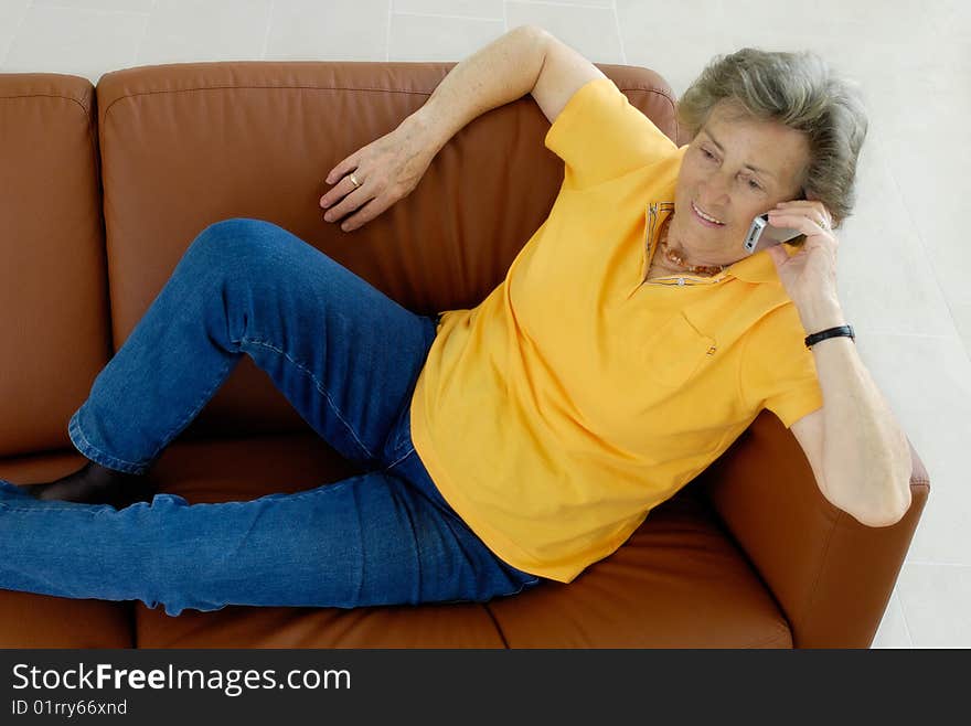 Senior woman with mobile phone on a couch