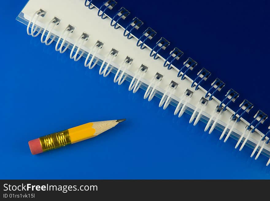 Short yellow pencil and notepads on blue ground. Short yellow pencil and notepads on blue ground