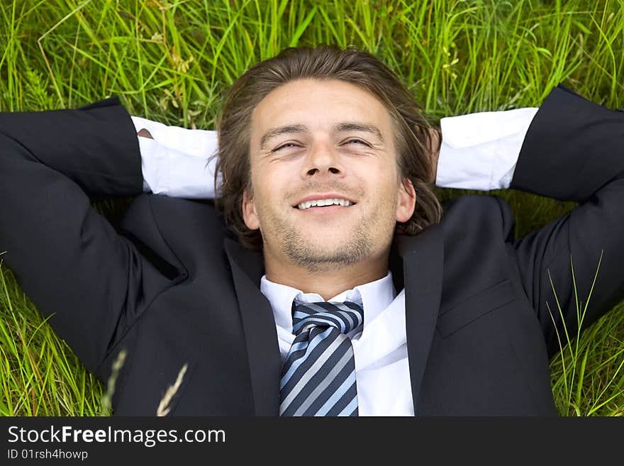 Well-dressed young businessman is resting in a field