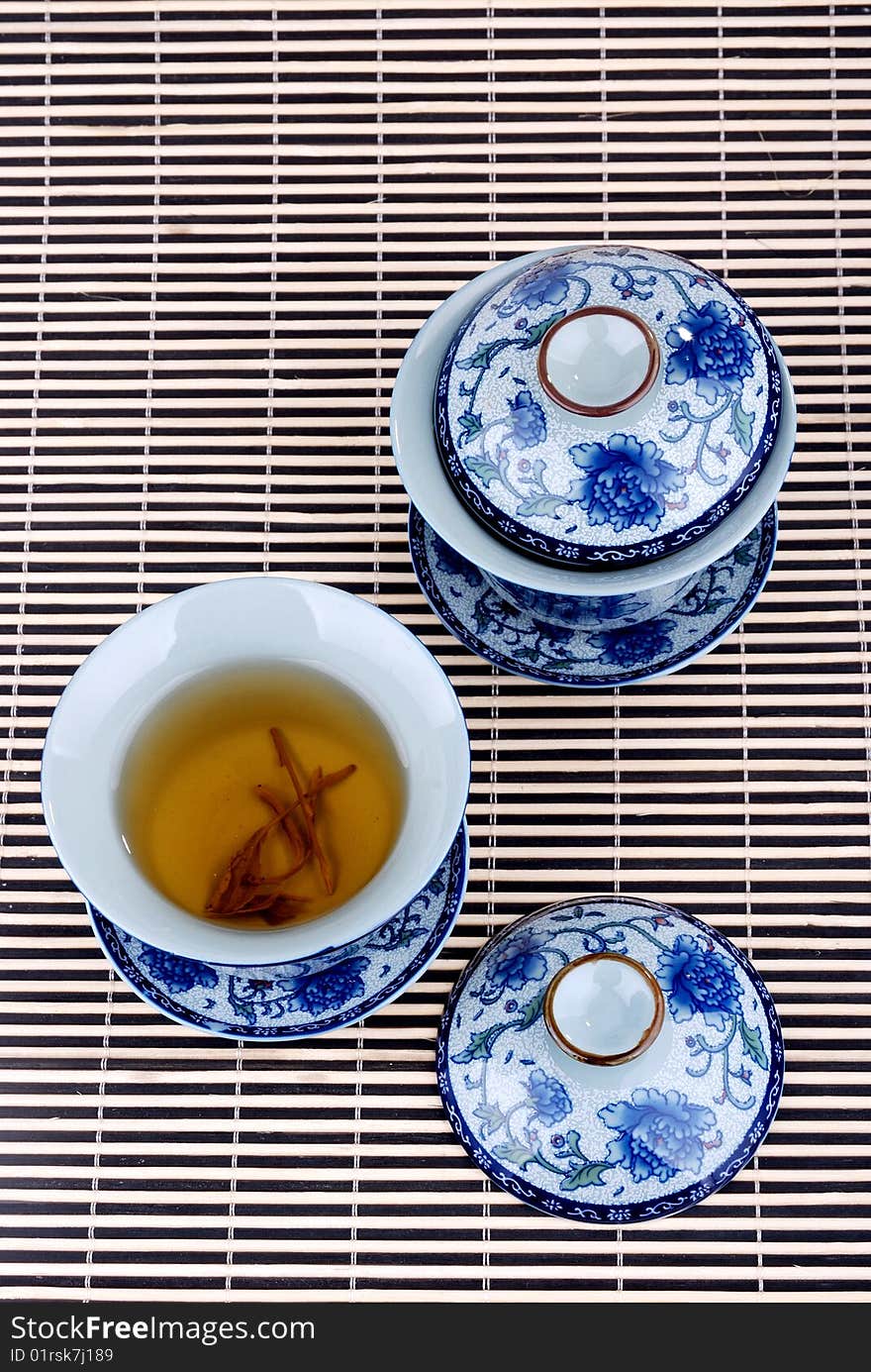 Green tea in a teacup with white teapot on the light background. Green tea in a teacup with white teapot on the light background.