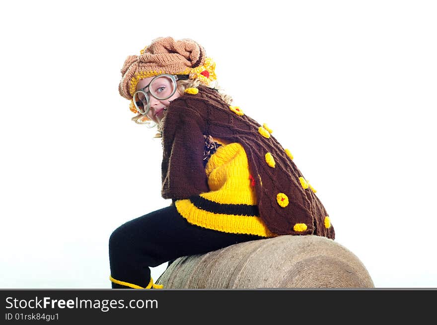 The girl in a knitted suit sits on the big ball of threads