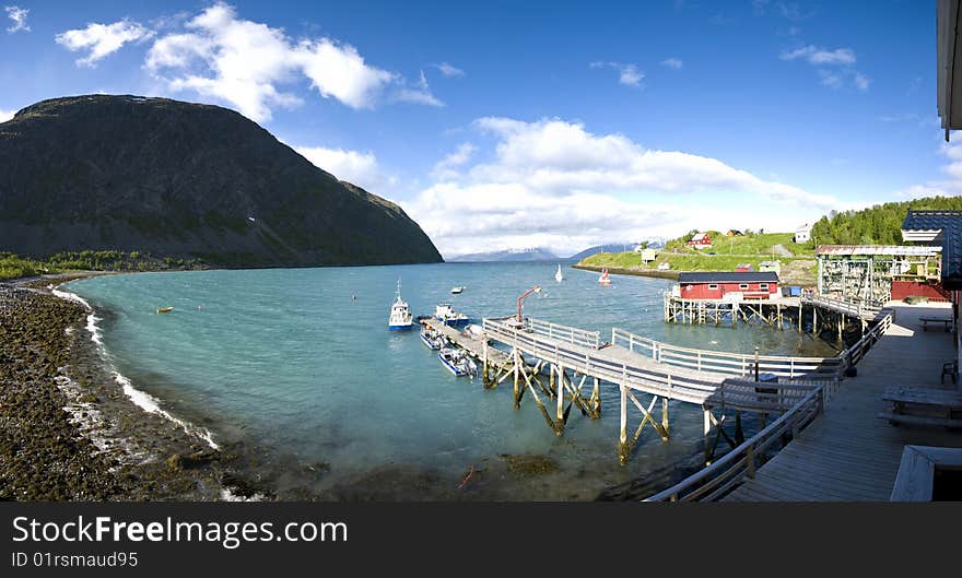 Panoramic view on Lyngenfjord, Koppangen village with fishing boats and pier. Panoramic view on Lyngenfjord, Koppangen village with fishing boats and pier.