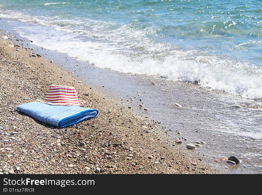 Pink sun hat on the towel next to sea. Pink sun hat on the towel next to sea.