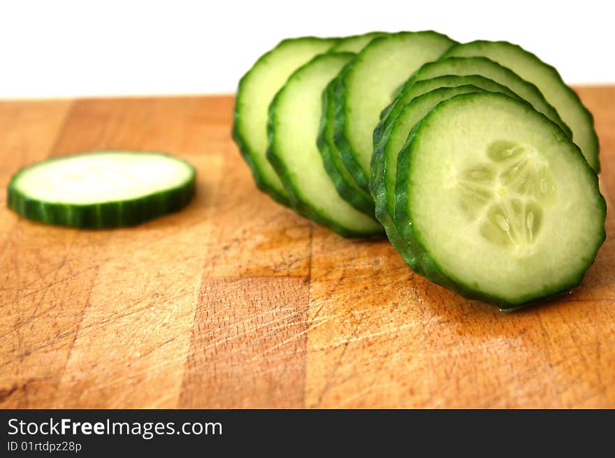 A cucumber in slices on top of kitchen surface. A cucumber in slices on top of kitchen surface