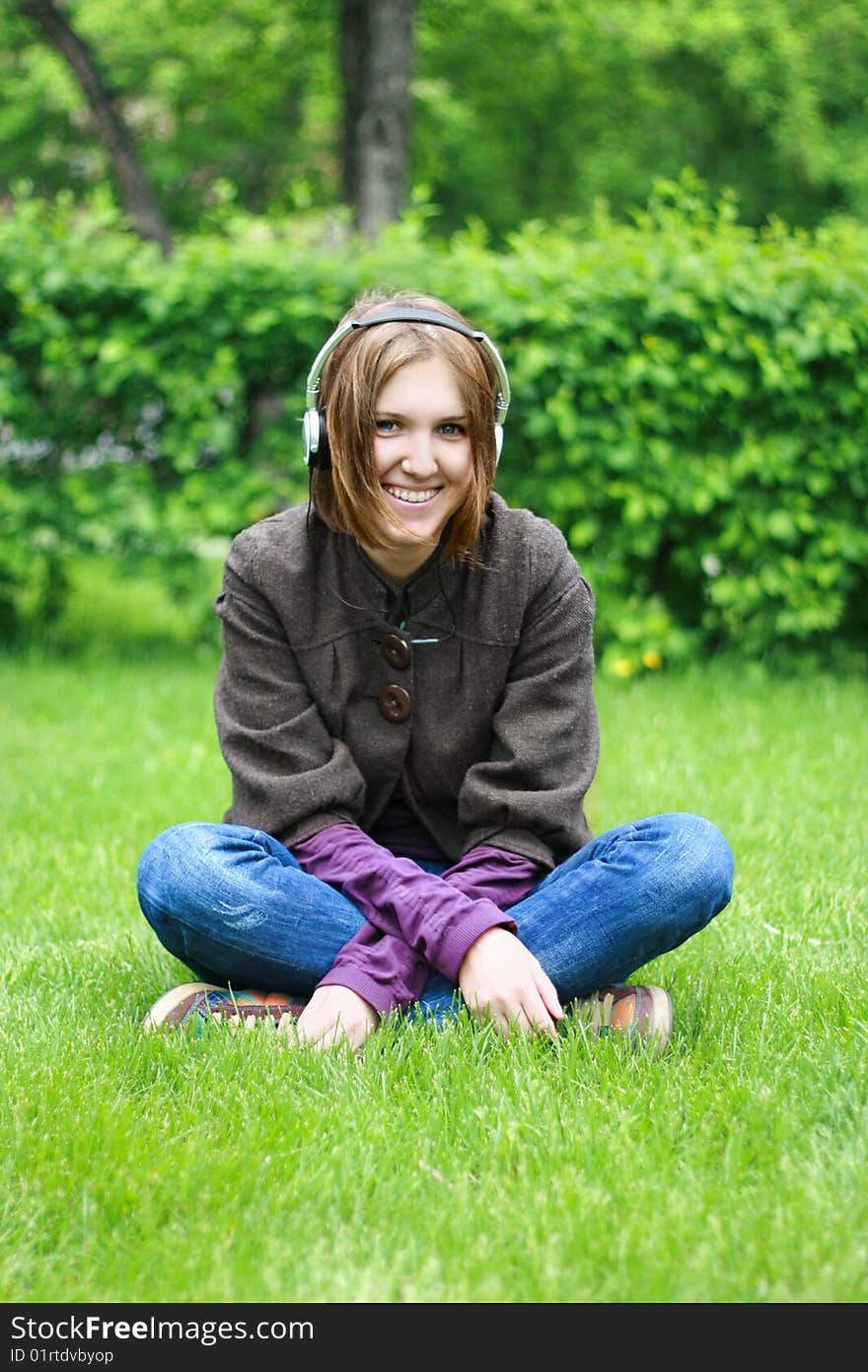 Beautiful girl listening music in ear-phones in park