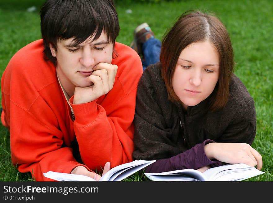 Young students couple reading a books. Young students couple reading a books