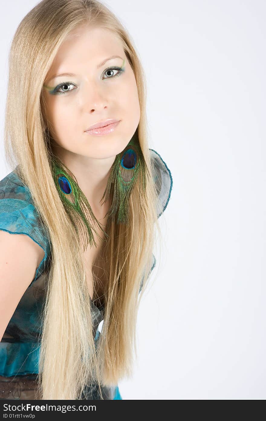 Beautiful young blond model with peacock earrings posing in studio shot. Beautiful young blond model with peacock earrings posing in studio shot