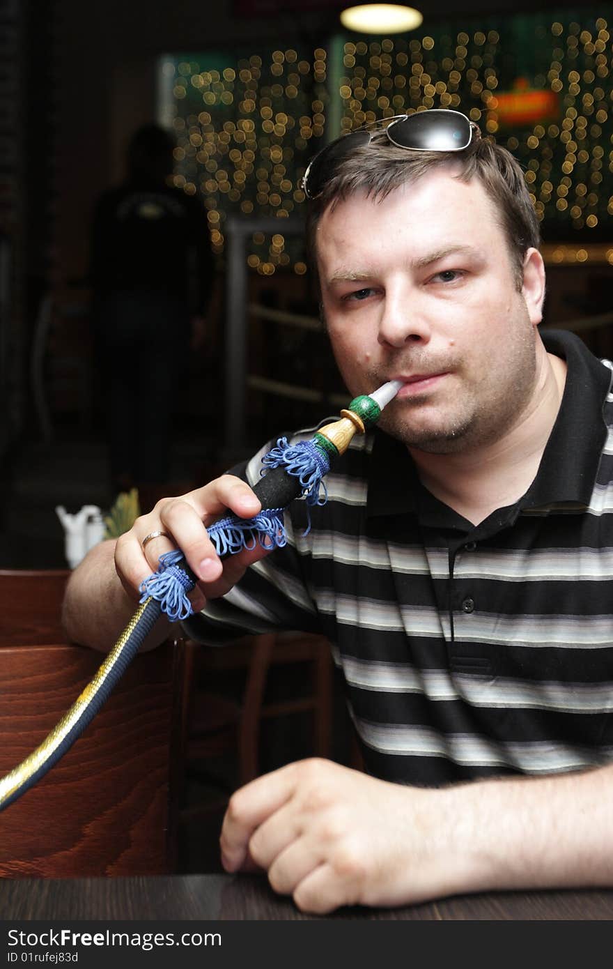 The man poses with a shisha in arabic cafe. The man poses with a shisha in arabic cafe