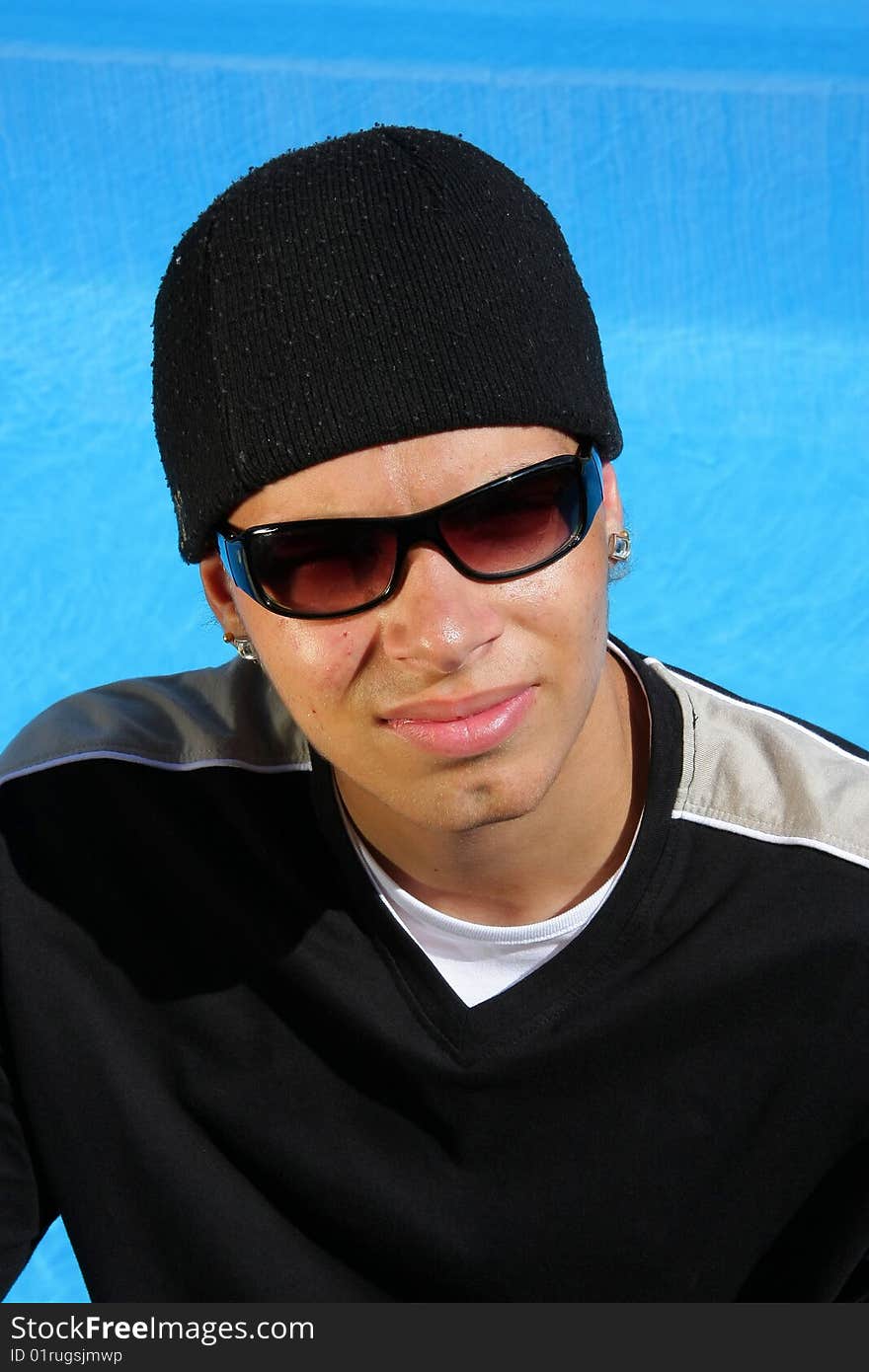 An arrogant looking teenager with sun glasses photographed in the summer sun sitting at a swimming pool. An arrogant looking teenager with sun glasses photographed in the summer sun sitting at a swimming pool